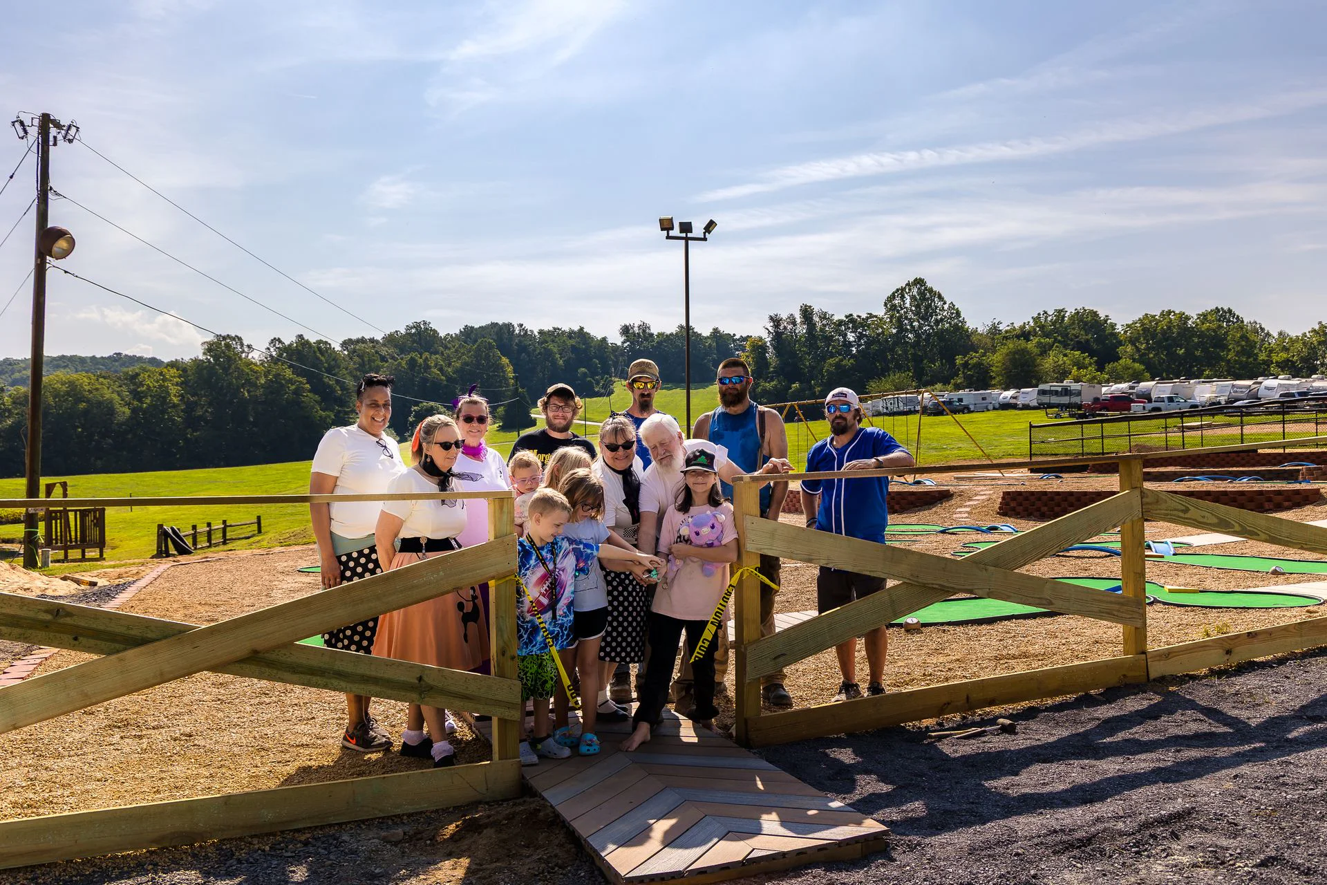 Families gathered at the fence of the new mini-golf course on a sunny day