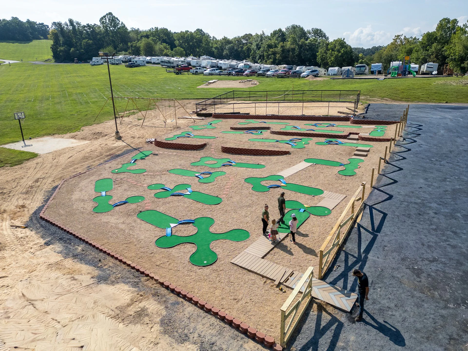 Elevated view of the mini-golf course with green holes beside the trees